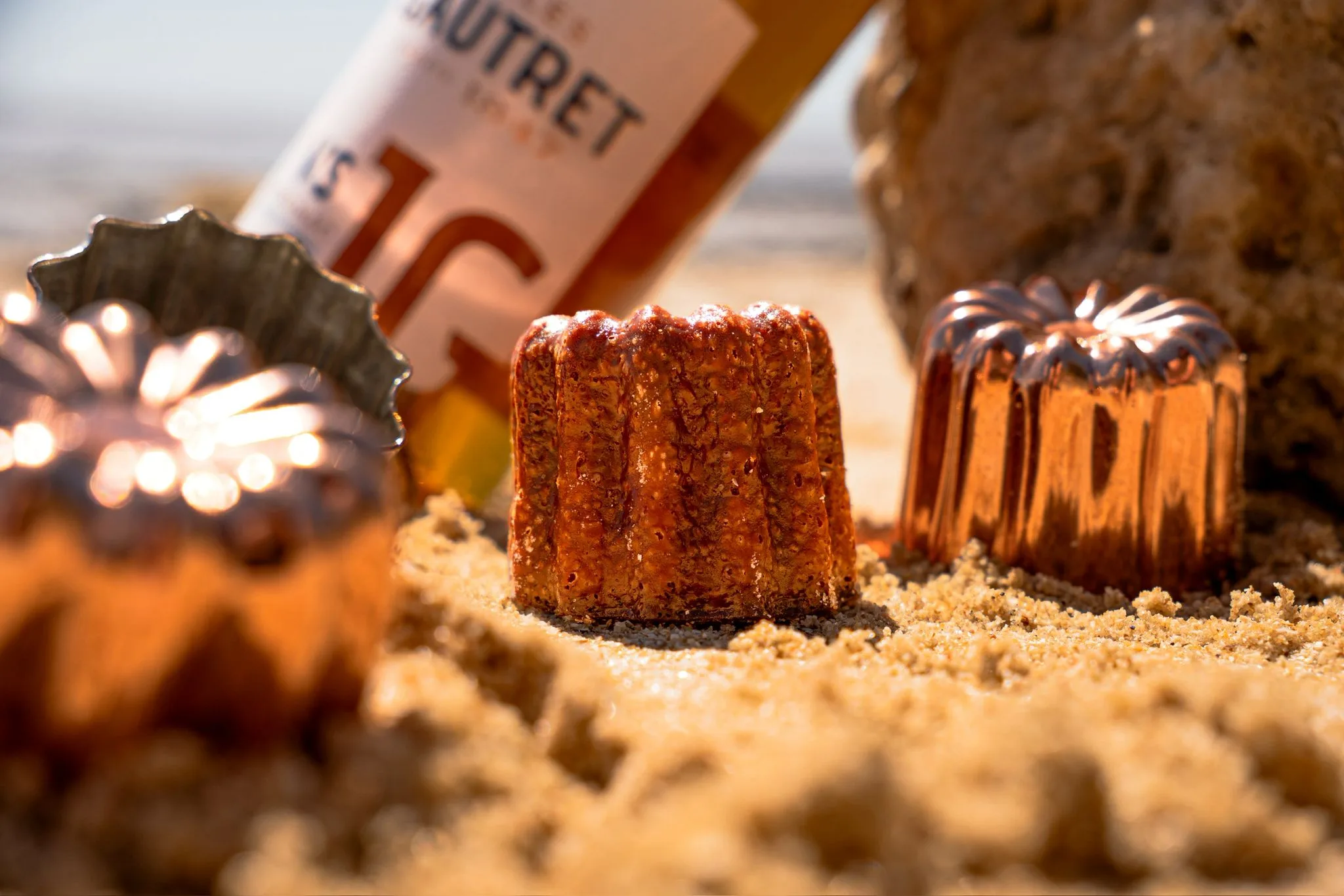 Cannelé et moules en cuivre dans le sable
